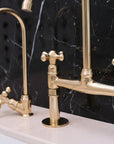 Gold kitchen faucet set against a black marble background