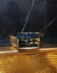 Brass Glass Rinser object with black central design on a marble surface