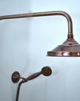 Vintage-style copper shower head and arm against a light blue background