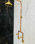 Vintage-style copper shower head and hose against a black and white marble wall.