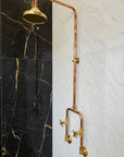 Handmade Copper Outdoor Shower and faucet system on a black and white marble wall.