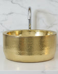 Gold metallic bowl on a white surface with a light gray tiled background