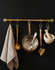 Kitchen utensils hanging on a gold rack against a black wall