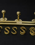 Set of gold-colored metal letter components on a black background