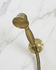 Vintage-style copper shower head and hose against a black and white marble wall.