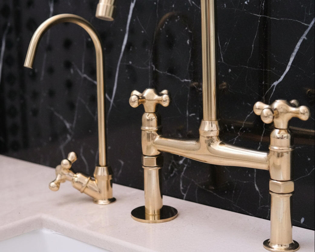 Gold kitchen faucet set against a black marble background
