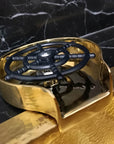 Brass Glass Rinser object with black central design on a marble surface