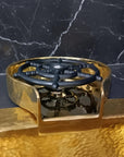 Brass Glass Rinser object with black central design on a marble surface