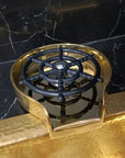 Brass Glass Rinser object with black central design on a marble surface