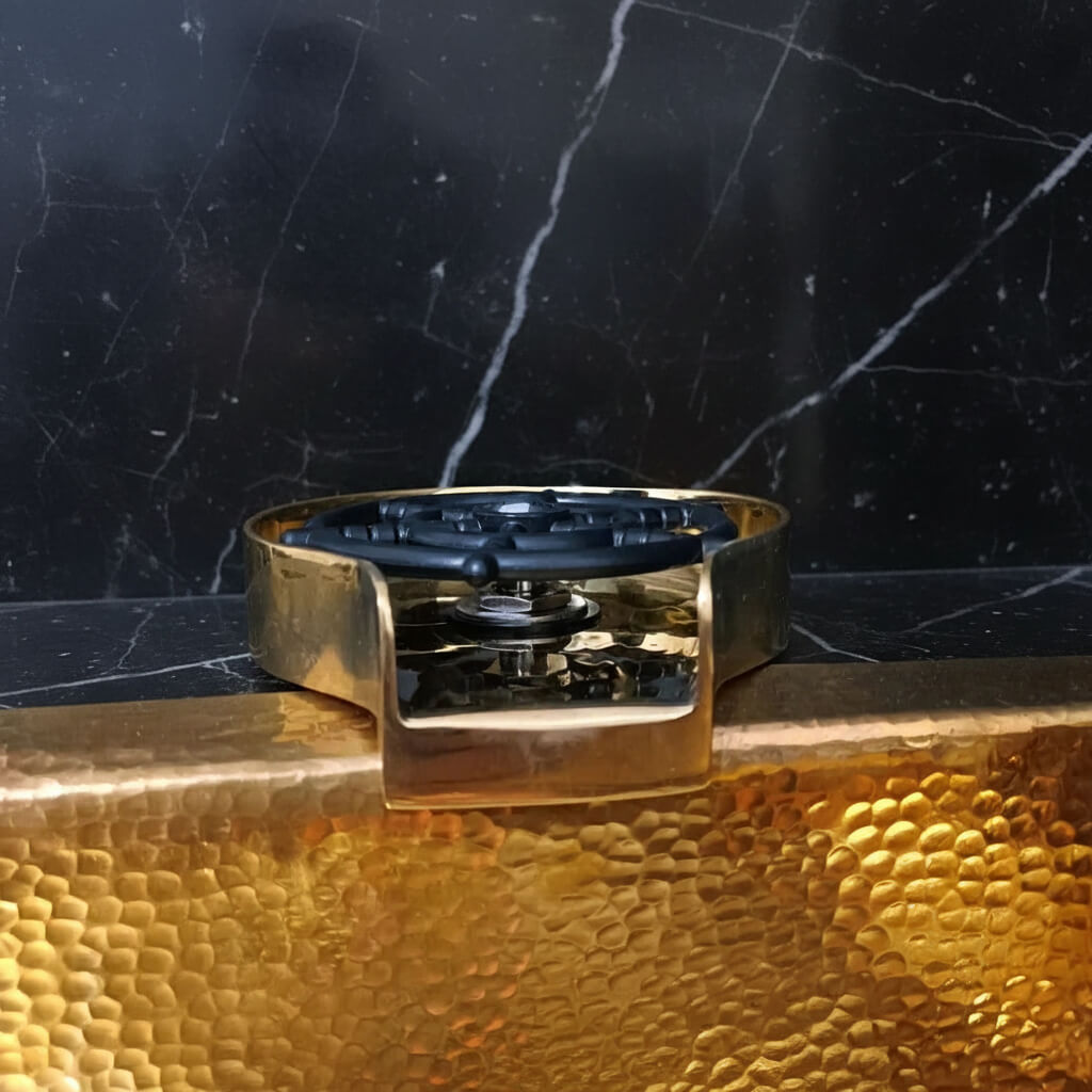 Brass Glass Rinser object with black central design on a marble surface