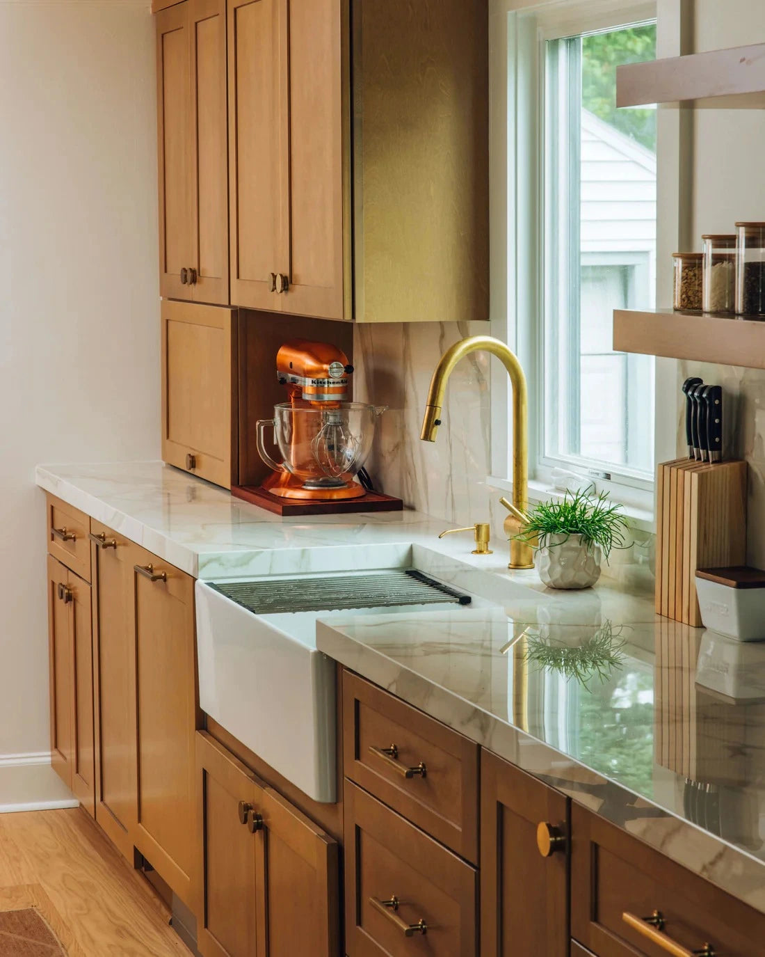 Modern kitchen with wooden cabinets, a white farmhouse sink, and a BRASS faucet.