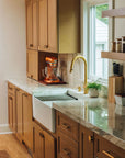 Modern kitchen with wooden cabinets, a white farmhouse sink, and a BRASS faucet.
