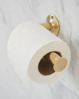 Brass toilet paper holder on a marble wall