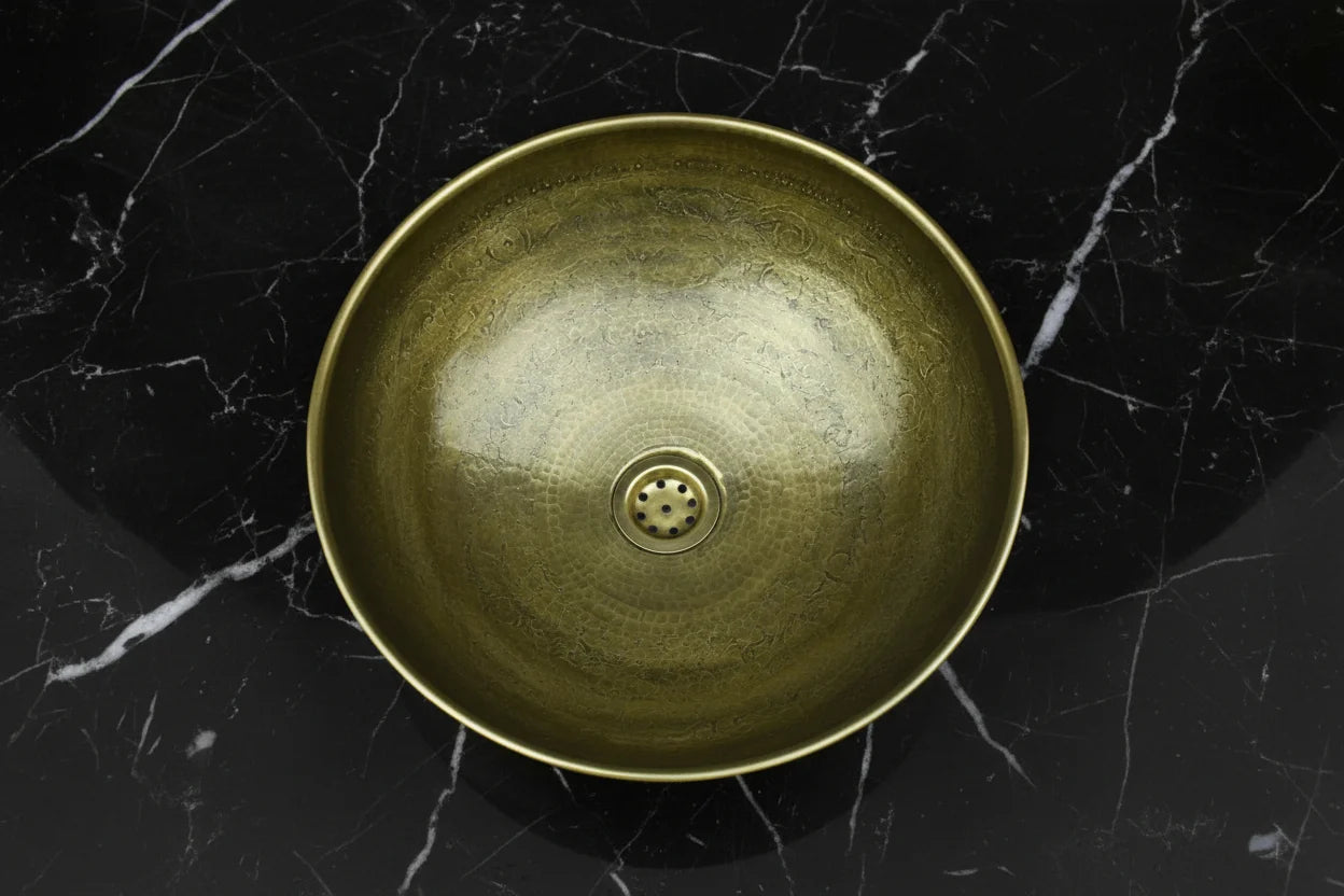 Bronze sink basin on a black marble surface