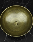 Bronze sink basin on a black marble surface