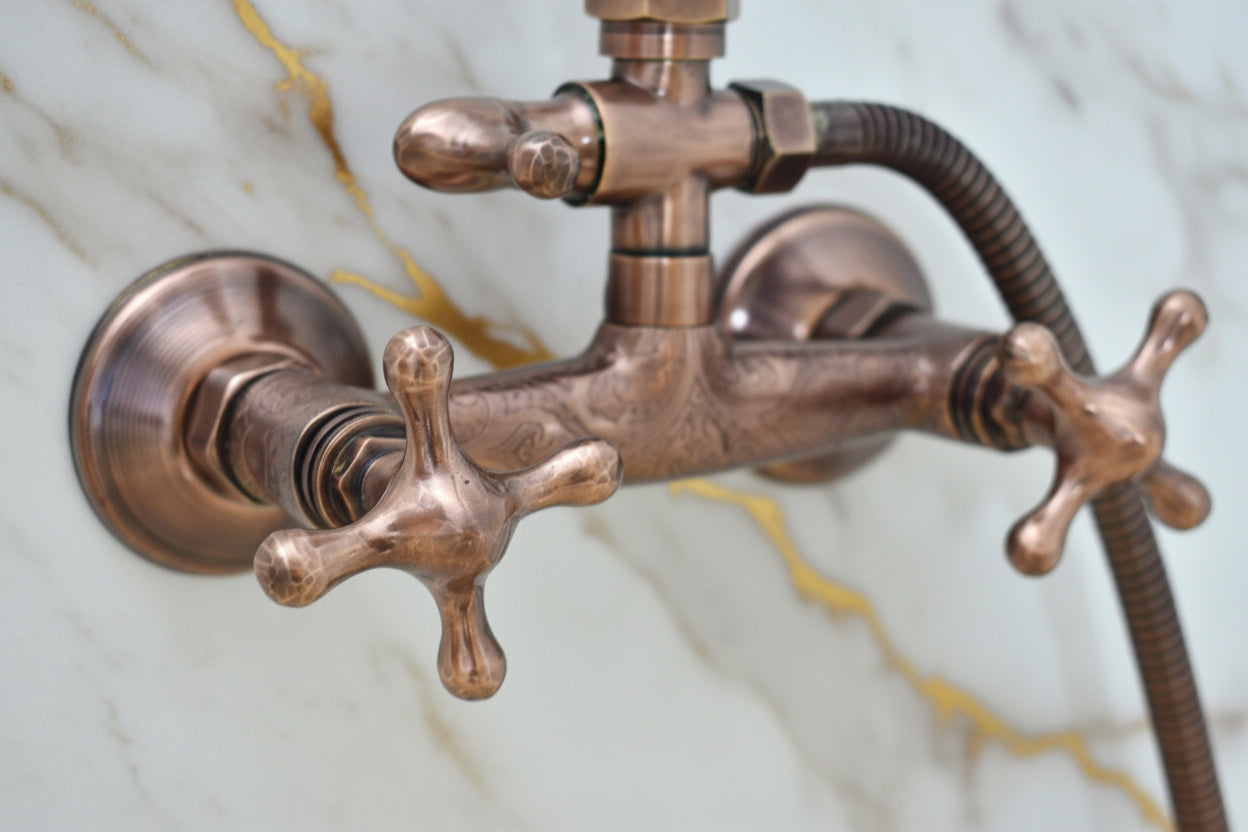 Close-up of a copper faucet with a hose on a light gray background
