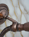 Close-up of a bronze shower head and valve on a light gray background
