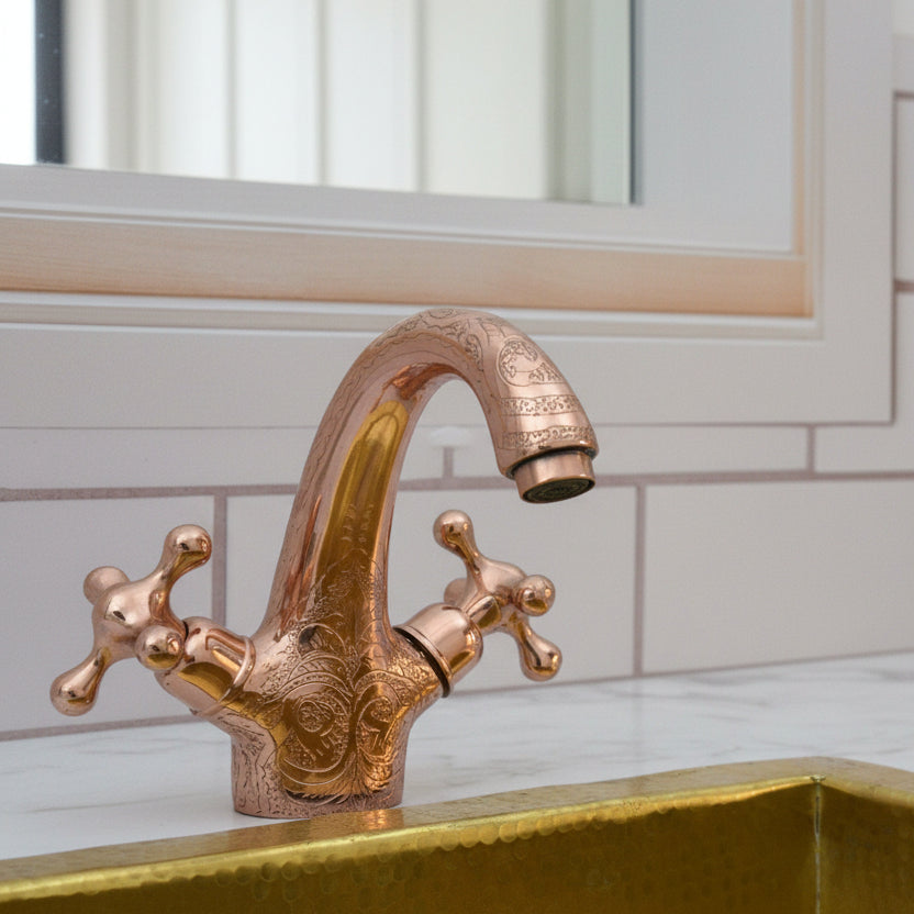 brass faucet on a marble sink with tiled wall background