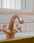 brass faucet on a marble sink with tiled wall background
