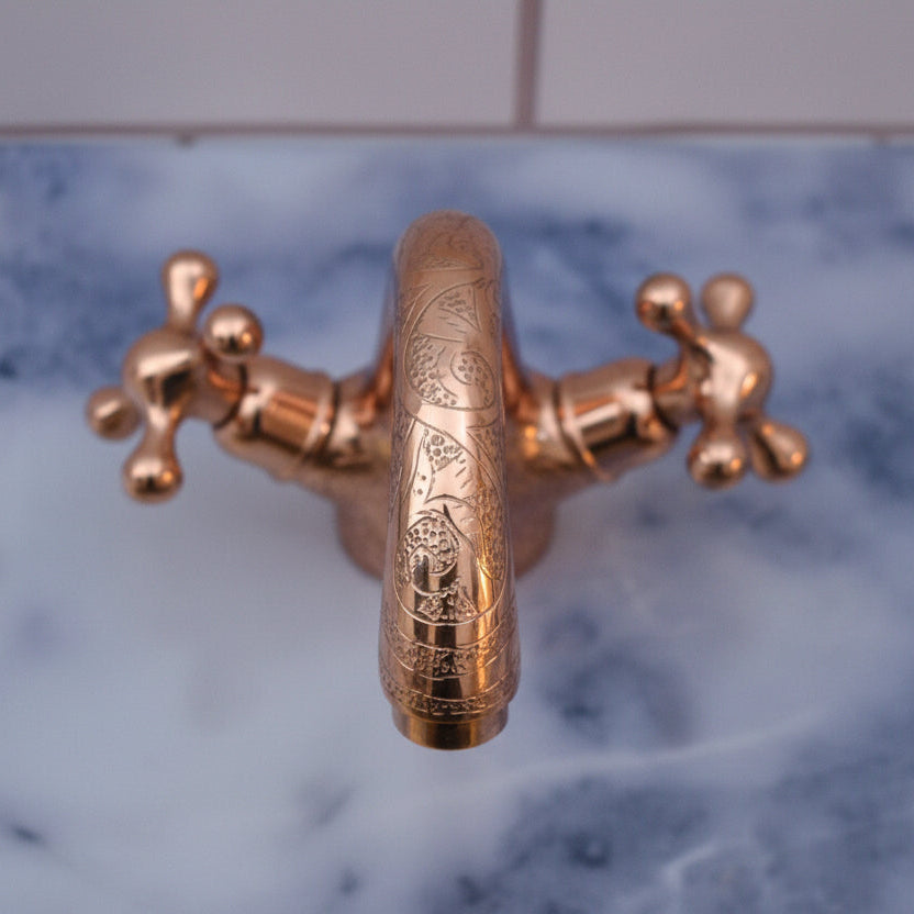 brass faucet with intricate design on a marble countertop