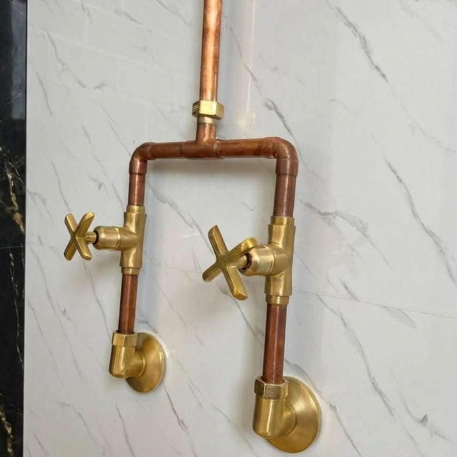 Brass and copper plumbing fixtures on a marble wall.