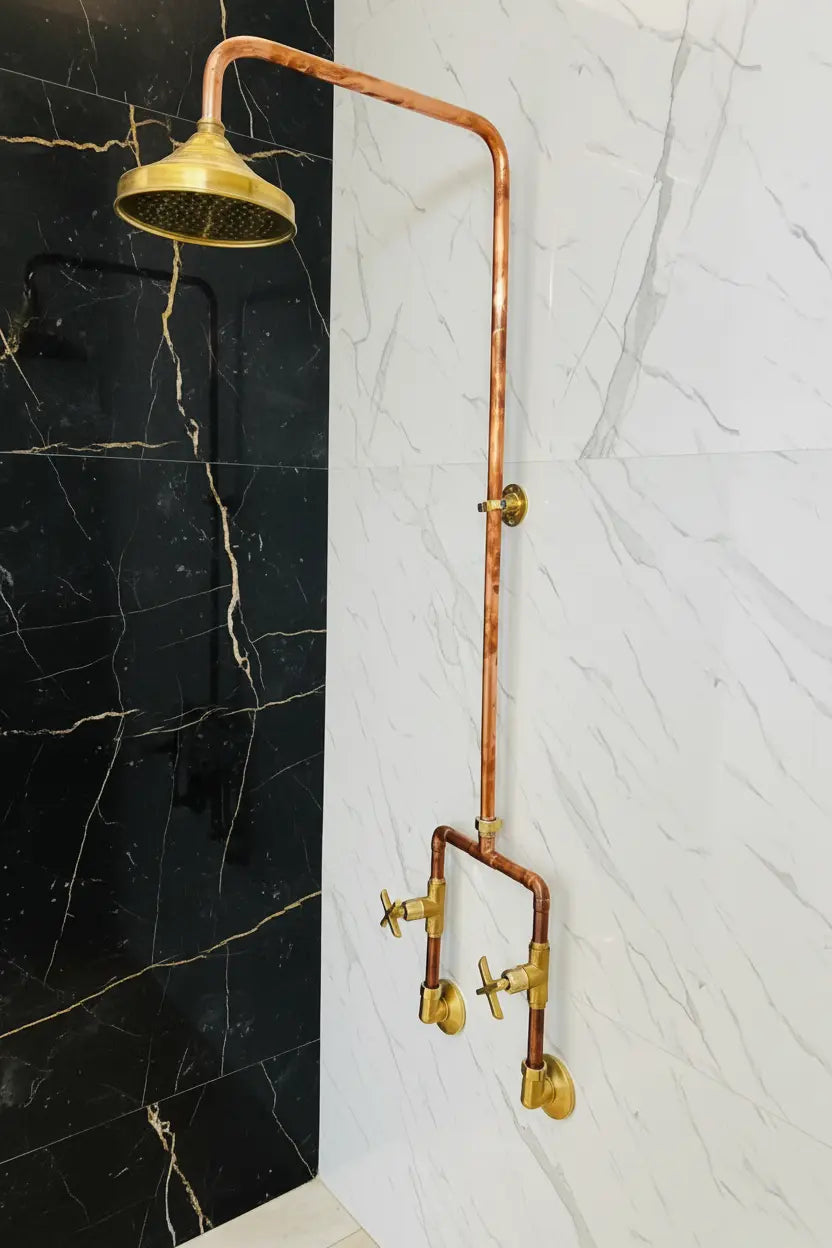 Vintage-style copper shower head and hose against a black and white marble wall.