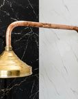 Vintage-style copper shower head and hose against a black and white marble wall.