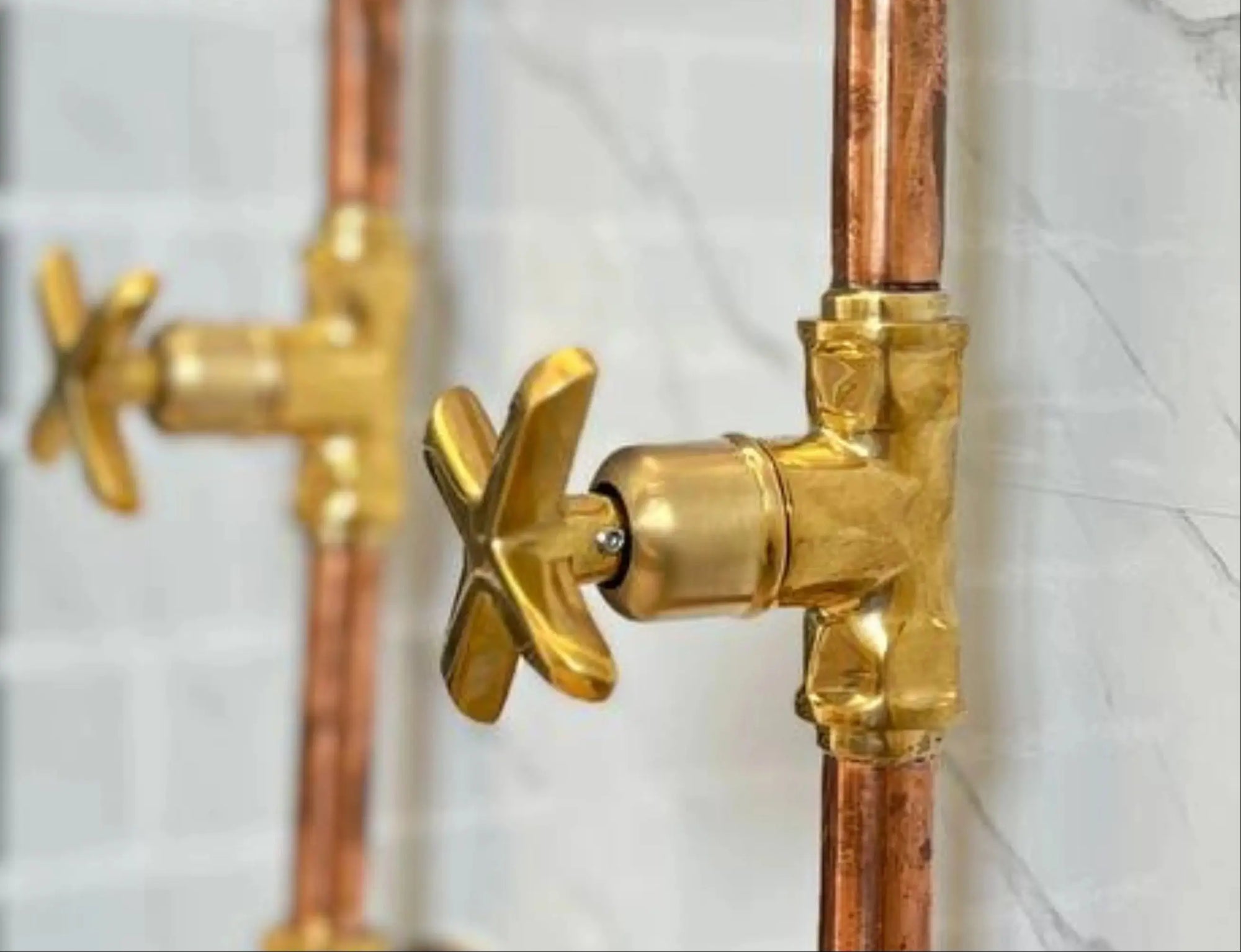 Handmade Copper Outdoor Shower and faucet system on a black and white marble wall.