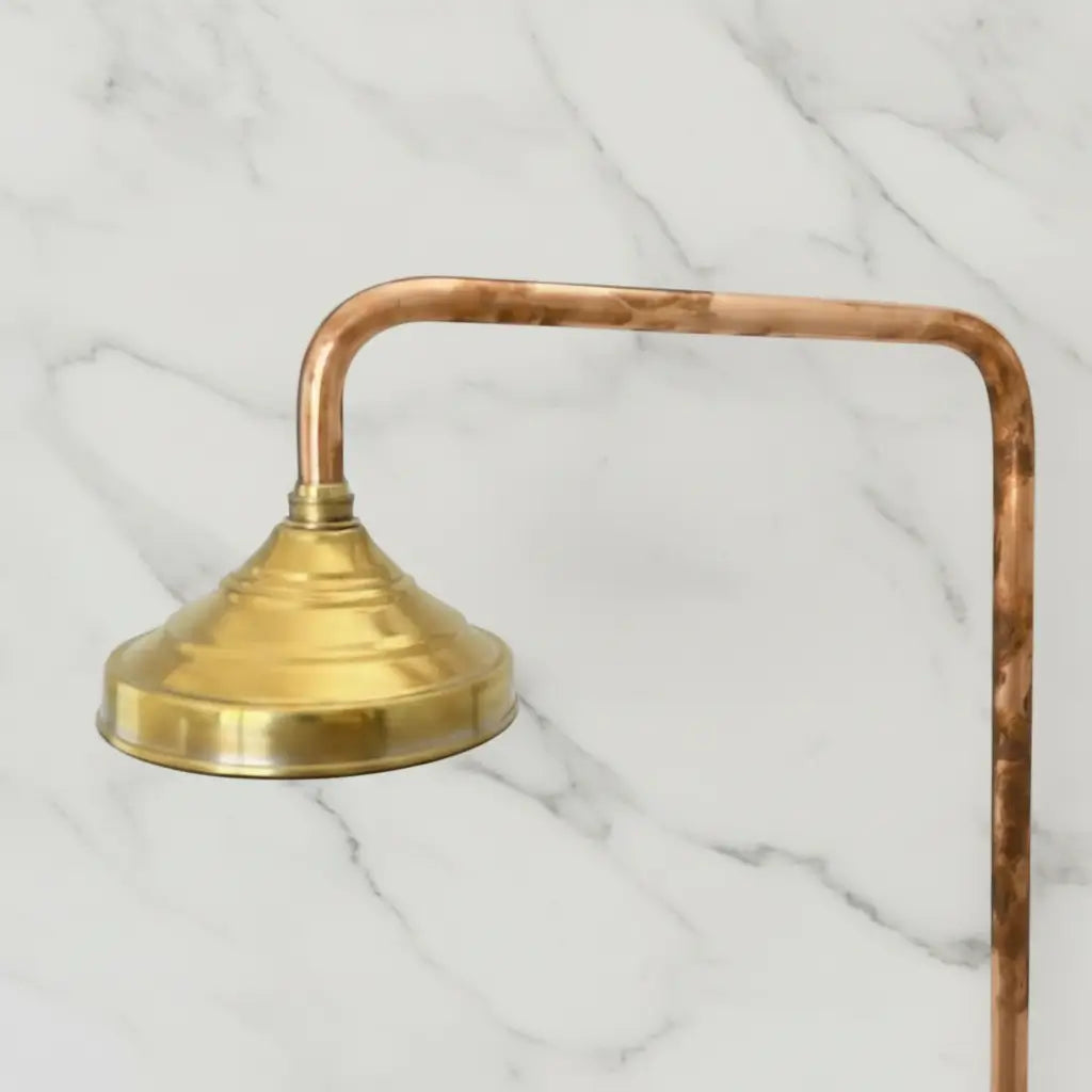 Brass shower head with copper hose on a marble background