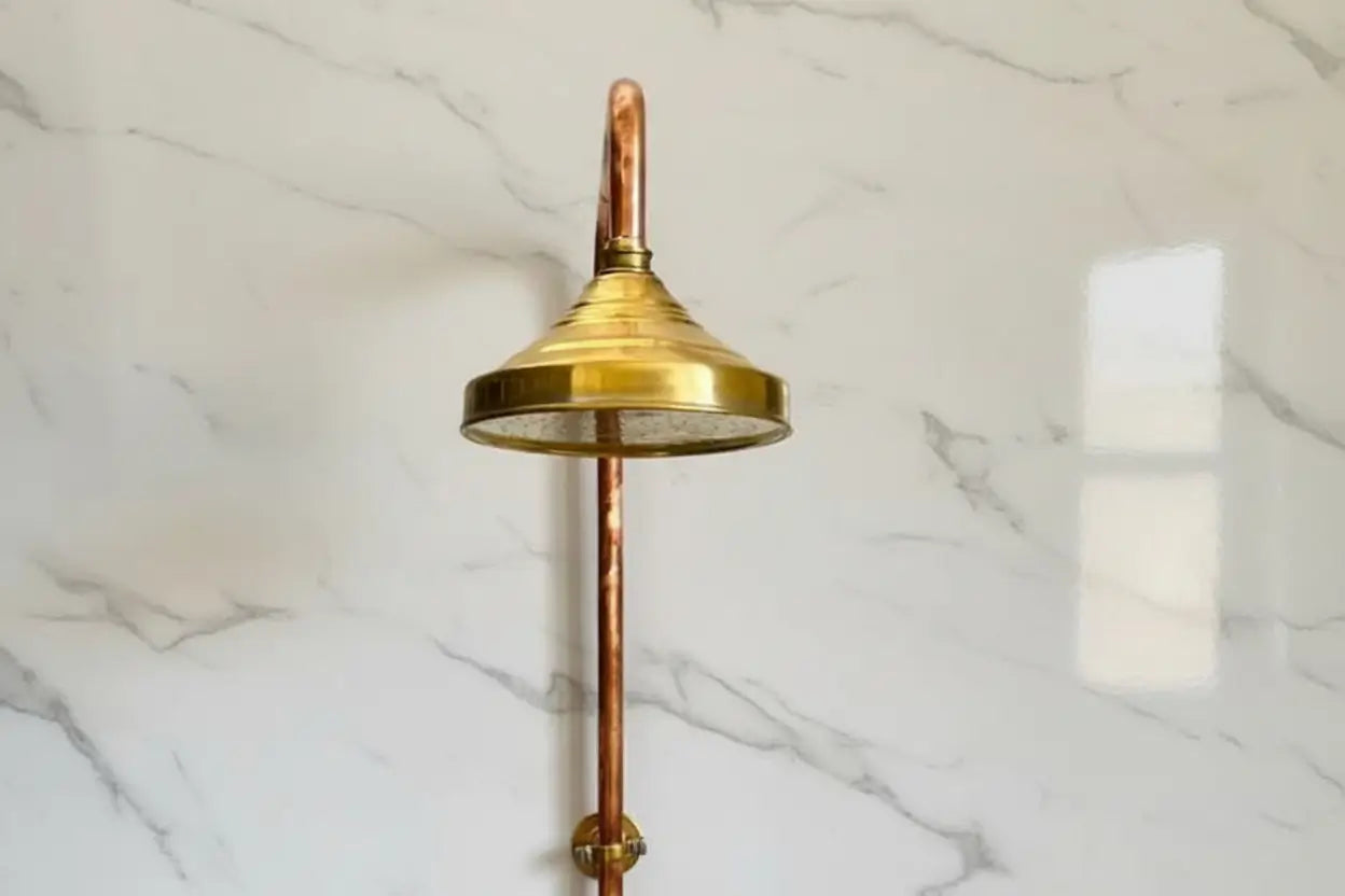 Brass shower head on a marble wall