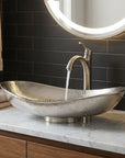 Bathroom vanity with a silver sink and faucet, illuminated mirror, and towels.