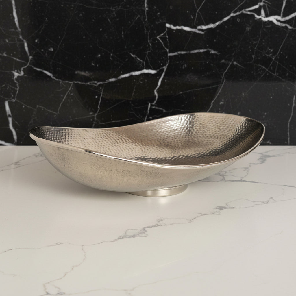 Silver hammered bowl on a white surface with a white background