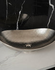 Hammered metal sink on a marble countertop with a black marble wall background