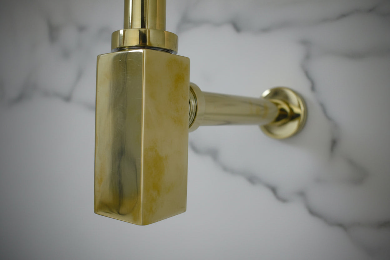 Solid Brass Bathroom Sink P-Trap mounted on a white wall 
