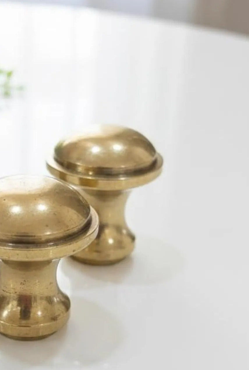 Two brass cabinet knobs on a white surface