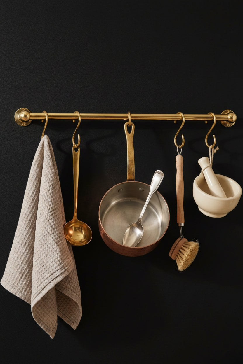 Kitchen utensils hanging on a gold rack against a black wall