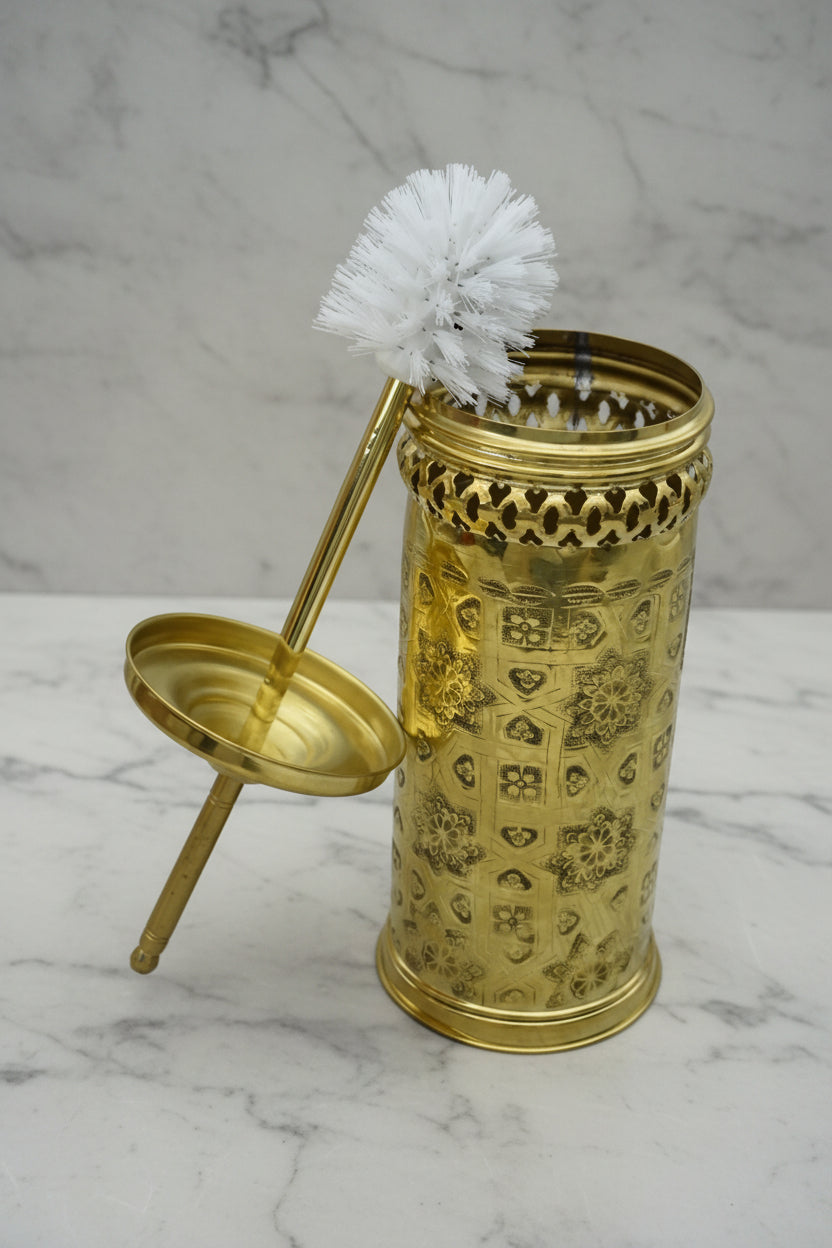 Decorative gold holder with a white brush on a marble surface
