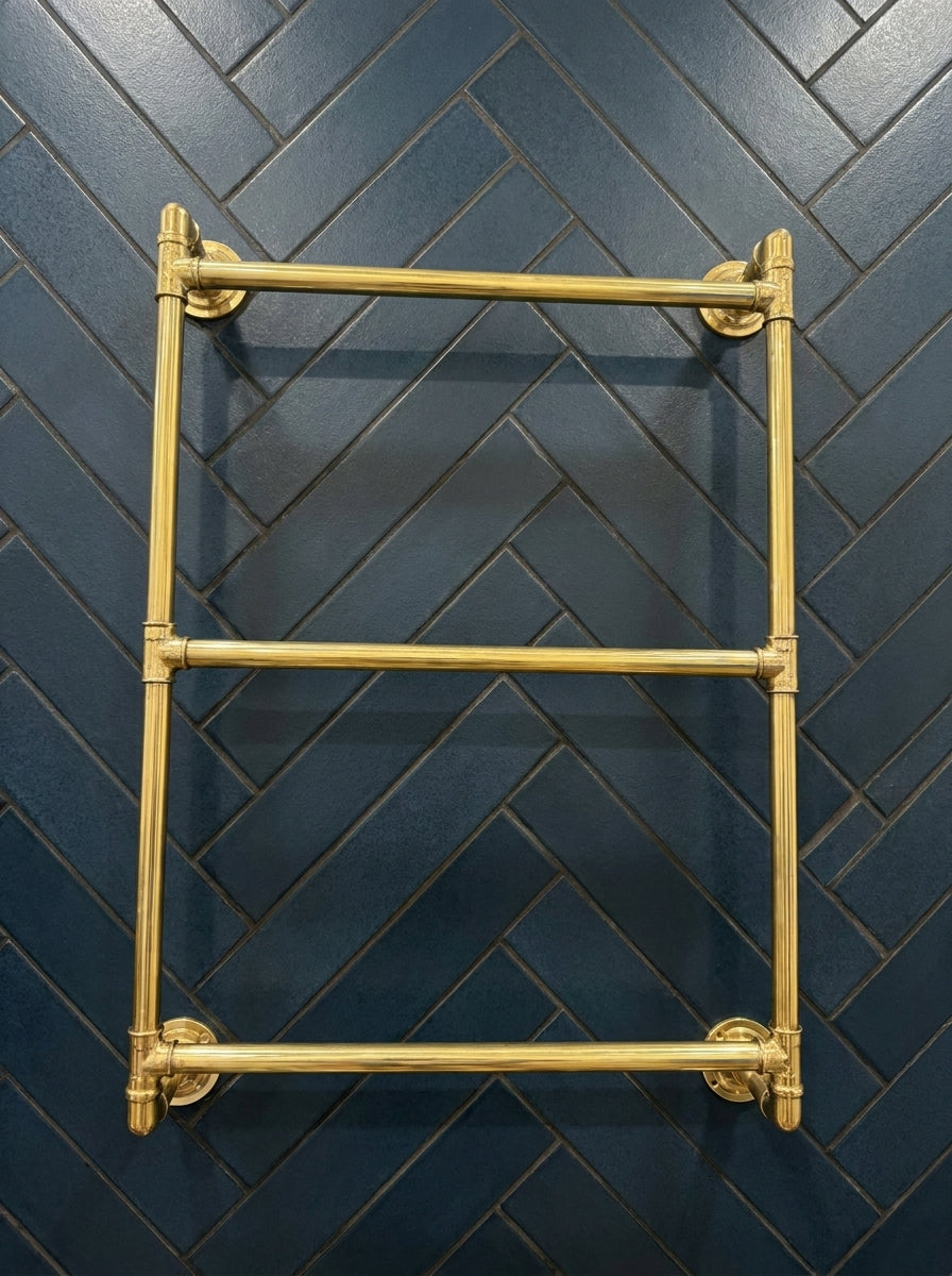 Gold towel rack against a dark blue tiled wall with a herringbone pattern
