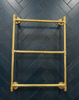 Gold towel rack against a dark blue tiled wall with a herringbone pattern