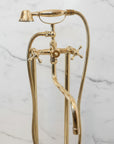 Unlacquered Brass Tub Faucet shower head and hose against a marble wall