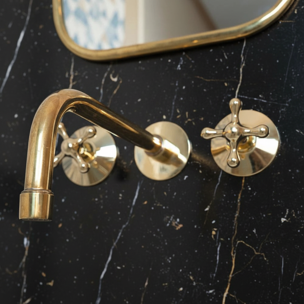 Brass bathroom faucet and handles on a black marble wall