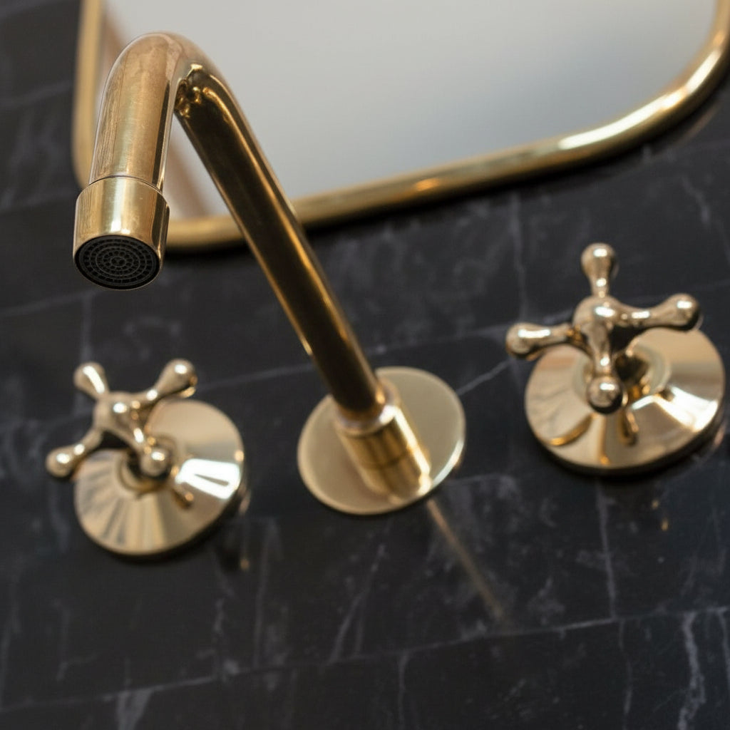 brass faucet and handles on a marble surface with a mirror in the background