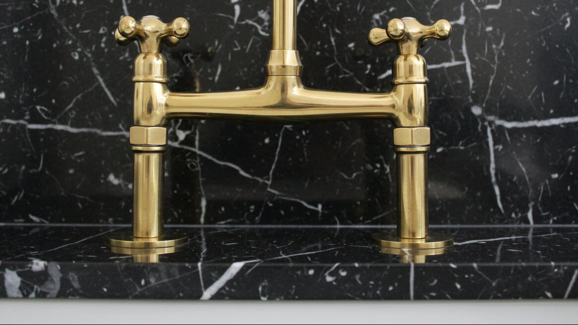 brass bridge faucet on a black marble background