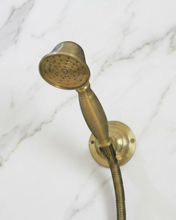 Vintage-style copper shower head and hose against a black and white marble wall.