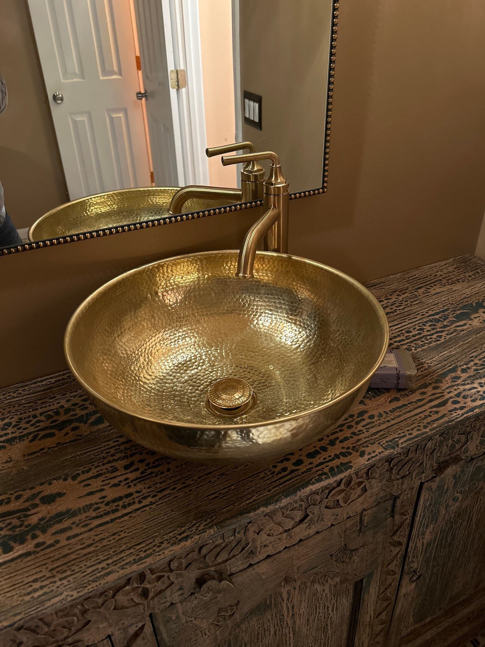 handmade Brass Vessel Sink on a wooden vanity with a mirror above