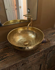 handmade Brass Vessel Sink on a wooden vanity with a mirror above