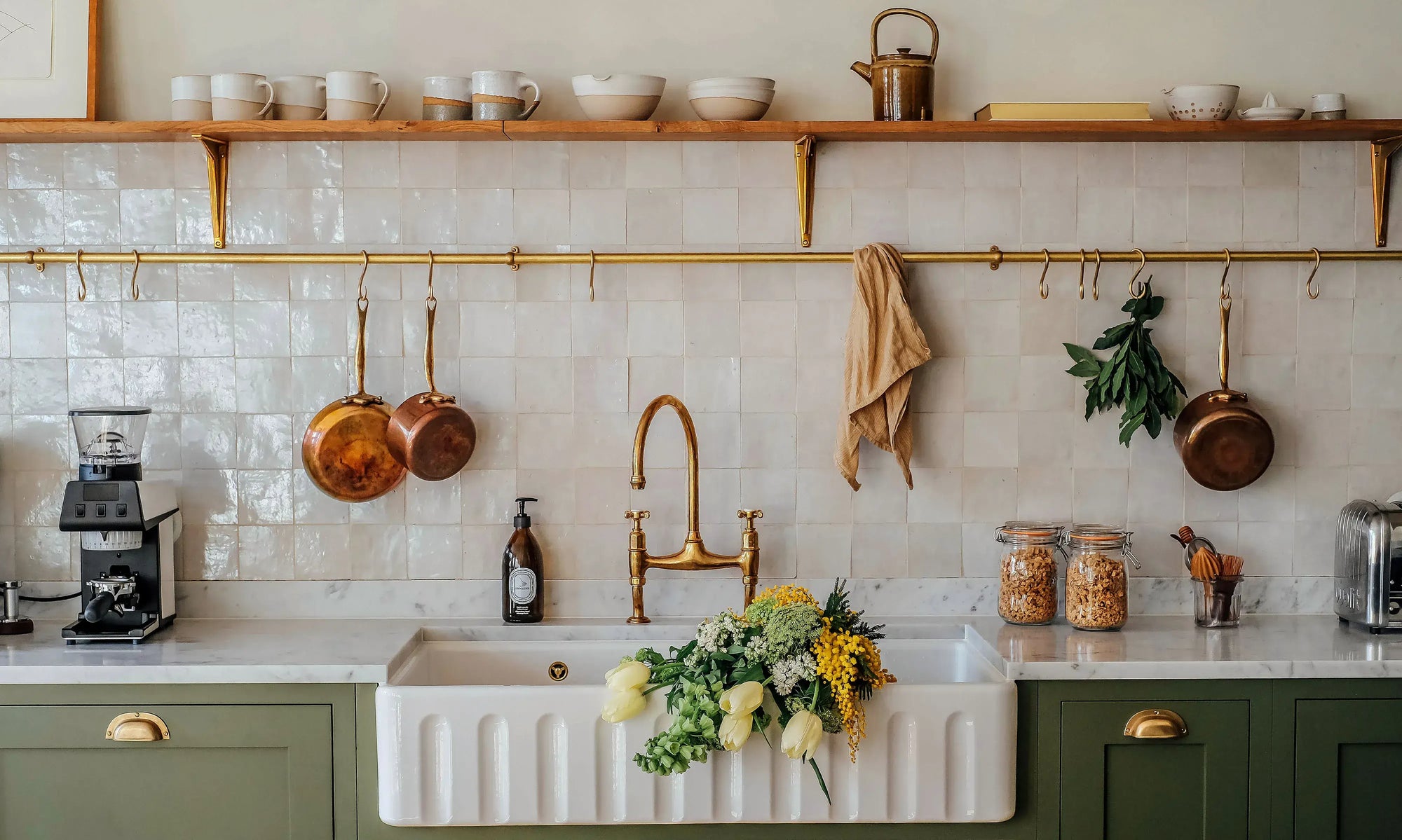 Modern kitchen with white sink, hanging pots, and a coffee maker.